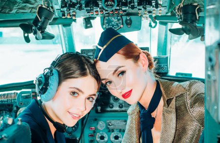 Retrato de dos mujeres pilotos sonrientes. Hermosa sonriente joven piloto sentada en cabina de aviones modernos. Azafata e instructor de vuelo en una cabina de aviones. Piloto y azafata