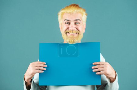 Bereich für Werbung. Glücklicher Mann mit leerer Plakatwand für Medienbanner. Verkauf. Überraschter bärtiger Mann mit leerem blauen Papier