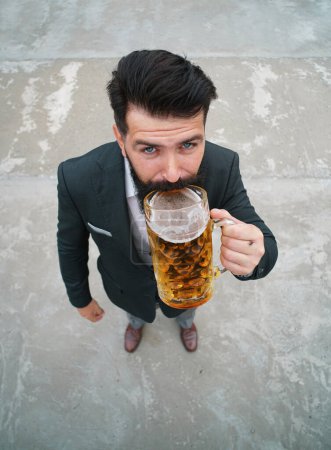 Téléchargez les photos : Longueur pleine, grand angle. Homme drôle boire de la bière à partir d'une tasse en verre - en image libre de droit