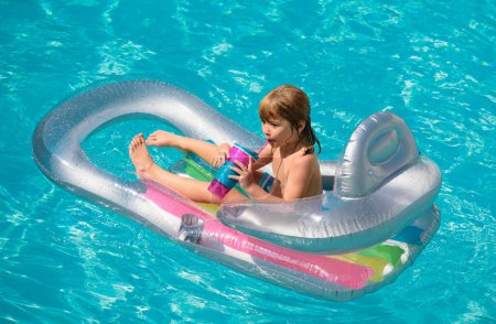 Téléchargez les photos : Les enfants sont heureux. Vacances d'été. Enfant dans la piscine. Garçon nageant à la piscine. Enfant drôle sur matelas gonflable en caoutchouc - en image libre de droit