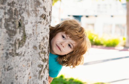 Photo for Hide and seek. Peekaboo. Little kid hide by tree. Kids vacation - Royalty Free Image