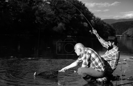 Téléchargez les photos : Pêcheurs amis et truites trophées. Pêche père et fils. Générations hommes pêchant dans la rivière - en image libre de droit