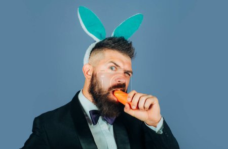 Téléchargez les photos : Joyeuse fête de Pâques et drôle de jour de Pâques. L'homme lapin mange de la carotte. Mignon lapin. Célébration Pâques - en image libre de droit
