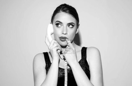 Photo for Charming girl holding phone handset, conversation on telephone. Portrait of woman with handset isolated studio background - Royalty Free Image