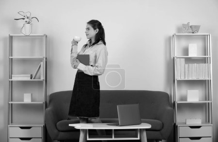 Foto de Joven empresaria con una taza de café en el lugar de trabajo en la oficina. Secretaria mujer en ropa formal trabajando en el proyecto en la oficina moderna - Imagen libre de derechos