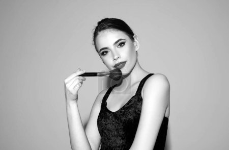Beautiful brunette young woman applying powder on her cheeks with a cosmetic brush. Beauty woman with clean healthy skin, natural make up, spa concept. Beautiful tender girl
