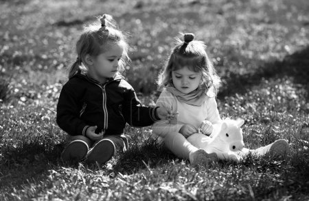Foto de Niños en pirnic. Lindo chico y chica se sientan en la hierba en el campo de verano. Bebé feliz niños jugando en hierba verde en el parque de primavera - Imagen libre de derechos