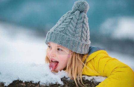Funny little girl walking eating snow on winter day. Excited christmas holiday. Kids cold and flu concept. Tongue with snow