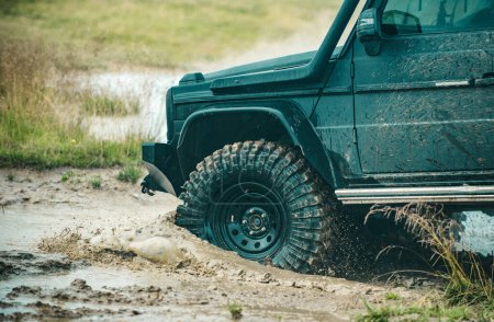 Off-road Jeep car on bad gravel road. Mud and water splash in offroad racing. Off-road travel on mountain road