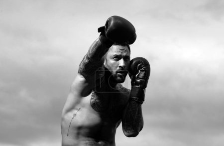 Téléchargez les photos : Boxer entraînement en plein air. boxeur masculin entraînement défense et attaques dans des gants de boxe. Forte boxe musculaire homme - en image libre de droit
