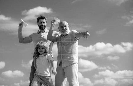 Männergeneration: Großvater Vater und Enkel spielen mit Spielzeugflugzeug im Freien am Himmel. Junge träumt davon, Pilot zu werden. Familienabenteuer, Fantasie, Innovation und Inspiration