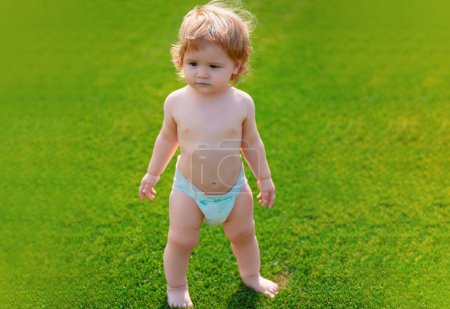Photo for Beautiful baby walking in the park in diaper pants. Healthy child - Royalty Free Image