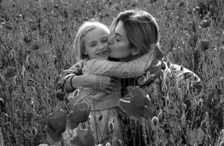 Téléchargez les photos : Mère et fille étreignant sur le champ de pavot fleuri. Vacances d'été en famille sur la nature. Été sur prairie de coquelicots avec des fleurs de coquelicots - en image libre de droit