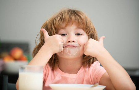 Portrait of cute child eating soup meal or breakfast having lunch by the table at home with spoon. Child nutrition. Kids healthy food