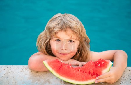 Foto de Un niño gracioso juega en la piscina. El niño come una sandía dulce, disfrutar del verano. Niñez despreocupada - Imagen libre de derechos