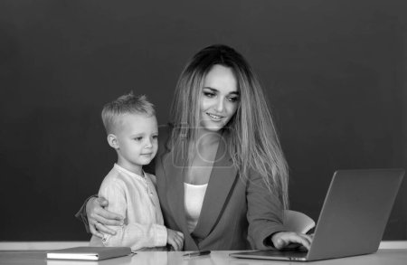 Photo for Mother and son learning. Teacher helping elementary school pupils in computer class, learning with laptop. Teacher helping school kids in classroom at school - Royalty Free Image