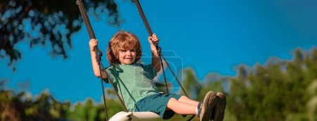 Banner with spring child face. Child swing on backyard. Kid playing oudoor. Happy cute little boy swinging and having fun healthy summer vacation activity