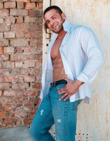 Photo for Macho man bristle. Male brutal style. Attractive guy in white shirt and jeans on urban background - Royalty Free Image