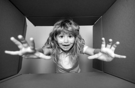 Foto de Niño feliz con caja de cartón, paquete de desembalaje de la tienda de Internet. Cliente de niños satisfecho con el servicio de entrega rápida. expresión infantil cara sorprendida - Imagen libre de derechos