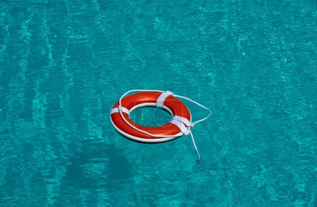 Foto de Cinturón salvavidas en el mar o la piscina. Anillo inflable naranja flotando en agua azul. Boya salvavidas para protección y seguridad de ahogamiento - Imagen libre de derechos