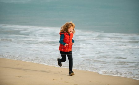 Foto de Kid running on beach. Happy child run in sea on summer vacation. Morning running with children - Imagen libre de derechos