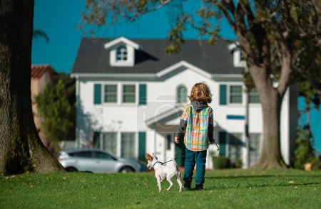 Foto de Niño pequeño paseando con el perro en el jardín. Feliz infancia. - Imagen libre de derechos