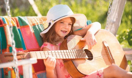 Téléchargez les photos : Musique et chansons pour enfants. Enfant musicien jouant de la guitare comme une rockstar. Joyeux mignon adolescent fille balançant et s'amusant sain vacances d'été activité - en image libre de droit