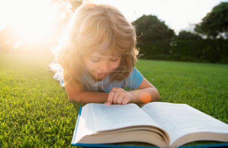 Foto de Lindo niño con libros al aire libre. Campamento de verano. Concepto de aprendizaje y educación para niños - Imagen libre de derechos