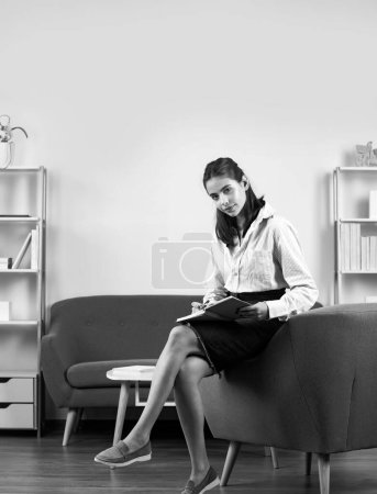 Photo for Young attractive secretary woman in a busy modern workplace in office. Pretty accountant girl at desk in office interior. Female student or young teacher girl - Royalty Free Image