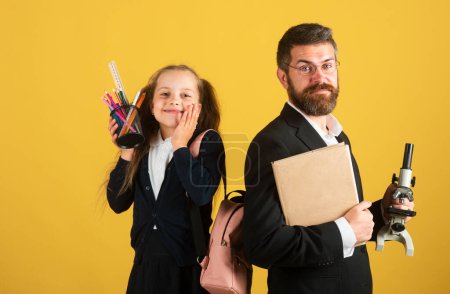Photo for Schoolgirl in school uniform and teacher having fun in studio. Portrait of amazed excited happy pupil school girl and tutor, isolated - Royalty Free Image