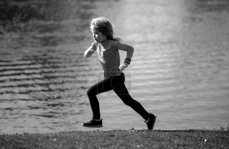 Téléchargez les photos : Enfant garçon courant dehors. Enfant coureur joggeur courir dans la nature. Jogging matinal - en image libre de droit