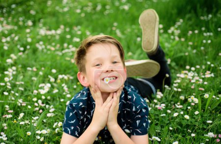 Foto de Humor despreocupado. Niño acostado en el fondo de hierba. Niño lindo disfrutando en el campo y soñando - Imagen libre de derechos