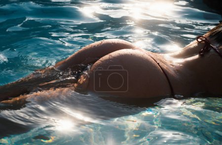 Foto de Primer plano de las nalgas de mujer en bikini. Vacaciones de verano. Parte del cuerpo de la niña delgada y en forma sobre el fondo de agua de mar - Imagen libre de derechos