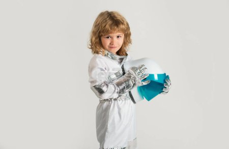 Téléchargez les photos : Small child wants to fly an in space holding astronaut helmet. Copy space - en image libre de droit