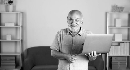 Foto de Consultor maduro, hombre mayor en el cargo. Un anciano en casa usando un portátil. Empresario senior con cuaderno - Imagen libre de derechos