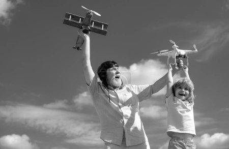 Foto de Nieto hijo y abuelo jugando con avión de juguete y dron quadcopter contra el cielo. Aviador piloto infantil con sueños de avión de viajar. Relaciones familiares Abuelo e hijo - Imagen libre de derechos
