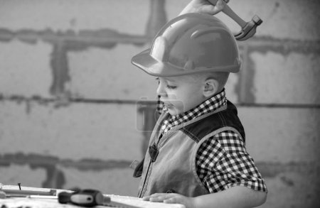 Téléchargez les photos : Portrait de petit constructeur en hardhats avec des instruments de rénovation sur la construction. Garçon constructeur, enfant charpentier avec ensemble d'outils constructeur. Constructeur et réparation d'enfants - en image libre de droit