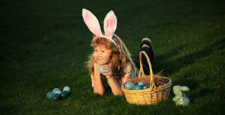 Foto de Huevos de Pascua en el jardín. Niño jugando en el campo, cazando huevos de Pascua. Bunny niños con conejo orejas de conejo - Imagen libre de derechos