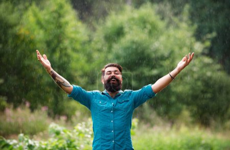 Foto de Concepto otoñal de clima lluvioso. Ropa impermeable. Hombre feliz bajo la lluvia - Imagen libre de derechos