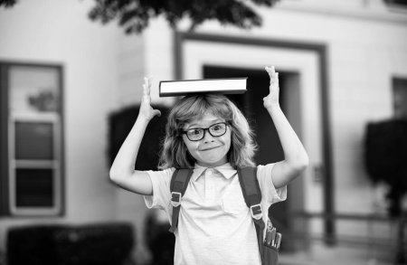 Back to school. Funny little boy in glasses at school. Child from elementary school with book and bag. Education child