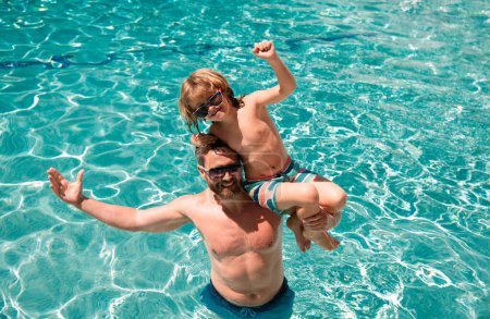 Foto de Padre e hijo en fin de semana de verano. Niño con papá jugando en la piscina. Fiesta en la piscina. Actividad deportiva - Imagen libre de derechos