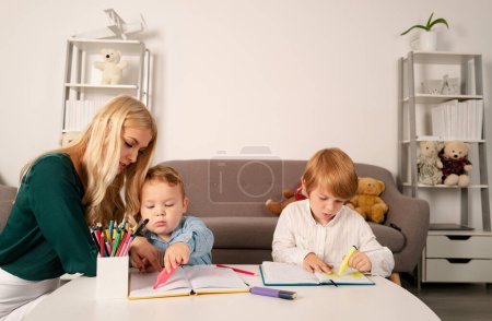 Photo for Mother and two son together draw, paint. Mom helps the children boys. Teacher mom working with creative kids. Children drawing in kindergarten - Royalty Free Image