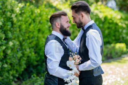 Photo for Gay man with partner on wedding day. Married LGBT couples celebrate a romantic wedding ceremony together with a bouquet flower. Portrait of happy gay couple on their wedding day outdoor - Royalty Free Image