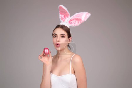Téléchargez les photos : Lapin de Pâques fille porter des oreilles de lapin moelleux de Pâques tenir des œufs de Pâques, fond de studio isolé. Portrait mangeur de lapin femelle - en image libre de droit