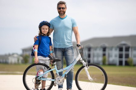 Assurance enfants. Père et fils font du vélo ensemble le week-end d'été. Joyeux papa ludique avec fils enfant excité en vélo le week-end. Famille sportive. Fête des pères