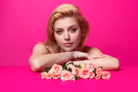 Foto de Retrato de estudio de belleza. Hermosa modelo con rosa rosa flor, aislado sobre fondo de estudio rosa. Encantadora joven con maquillaje perfecto - Imagen libre de derechos