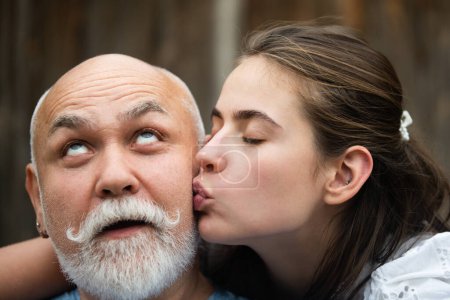 Foto de Niña besando al abuelo, de cerca. Viejos y jóvenes Pareja enamorada besándose. Momento romántico. Beso de ensueño - Imagen libre de derechos