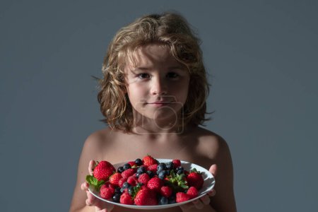 Healthy food. Close up summer portrait of kid with plate of mix summer fruits. Healthy organic strawberry fruit, summer season