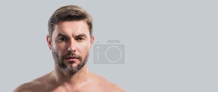 Close up beauty portrait of satisfied man after facial cream. Attractive brunet guy touching skin. Men model face with beard and modern haircut. Banner for header, copy space. Poster for web design