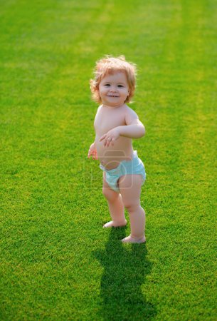 Photo for Cute funny laughing baby learning to crawl, having fun playing on the lawn watching summer in the garden. Happiness and harmony in family life - Royalty Free Image